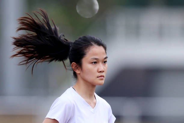 A female softball team practices on a lush, suburban field in Tokyo, emphasizing both collaboration and athletic skills in preparation for their matches.
