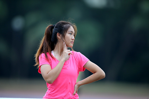 An Asian young woman is doing warm up exercise for sports training routine