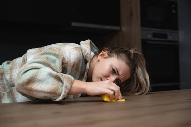 young woman apartment owner for rent has rented out the apartment to students who left dirt and stains that she tries to clean and remove with a scrubbing sponge in order to rent out to new tenants - obsessive imagens e fotografias de stock