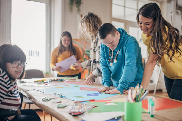 People with down syndrome and cerebral palsy doing an art project with help with assistants and animators.Disability health care art workshop.