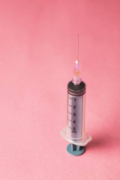 istock Closeup of a syringe with a needle on a pink background 1479340954