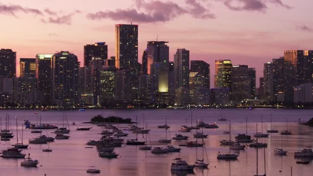 Aerial of boats with the illuminated Chicago skyline during the pink sunset in the background