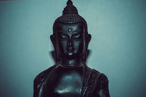 An isolated black statute of Buddha with closed eyes meditating