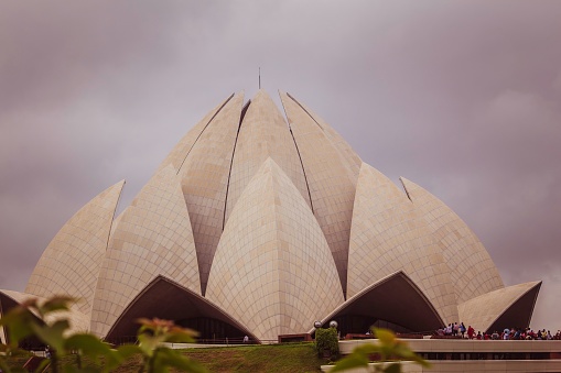A group of people leisurely stroll through the grounds of the iconic Lotus Temple in Delhi, India.