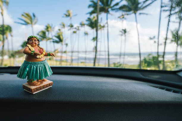istock Hawaiian Hula dancer doll sitting on car dashboard with palm trees in background 1479341837