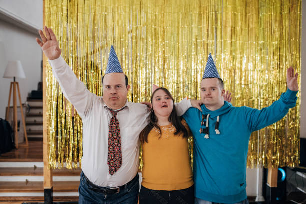 Three friends with down syndrome hugging at the party and wearing party hats