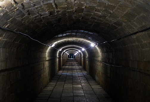 Secret underground passage, illuminated by electric lamps. Conduit. Escape concept.