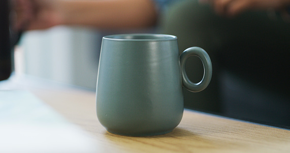 Ceramic, coffee and mug on a wood counter in a kitchen for a morning routine warm beverage. Tea, cappuccino and blue clay cup on a table for a breakfast drink in a modern home, house or apartment.
