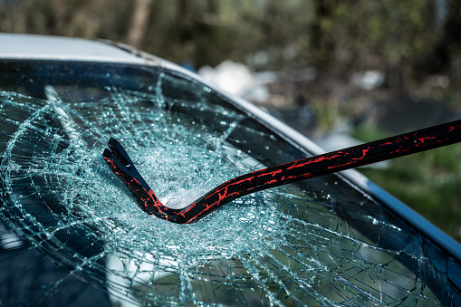 Close-up of bullet hole on glass against black background.