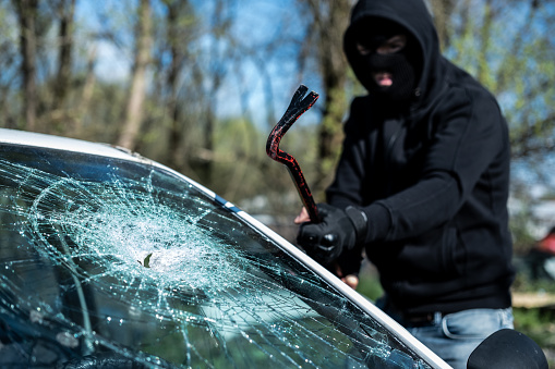 Thief breaking car glass. Vandalism.