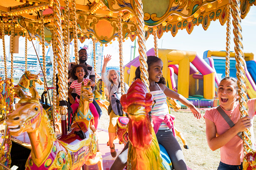 A family enjoying a day out together at the fair in Newcastle upon Tyne, North East England. They are riding on different creatures on the carousel and are all looking excited.