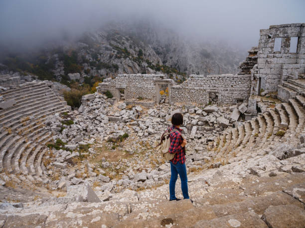 Autumn walk , woman looking at the ancient amphitheatre in city Termessos Ancient City, Turkey. Turkeys most outstanding archaeological sites and one of main tourist center.