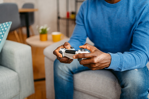 Close-up of young man playing video games on a joystick at home.