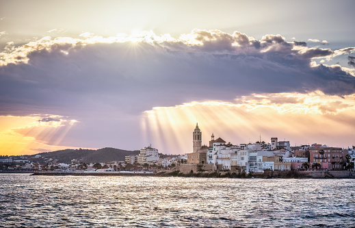 Sitges at sunset with sun rays between the clouds. Catalonia. Spain