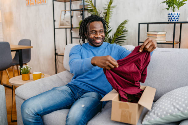 istock Young Man Unboxing A Package With A New Shirt He Ordered Online 1479353002