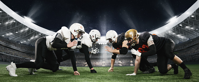 Start of competition. Professional american football players, men in uniform standing in position at open air 3D stadium with flashlights and blurred stands. Concept of sport, match, action, game