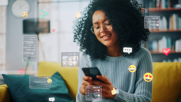 istock Social Media Visualization Concept: Happy Black Woman Uses Smartphone at Home. 3D Representation of Social Media Posts, Smiley Faces, e-Commerce Online Shopping Digital Icons Flying Around the Device 1479353193