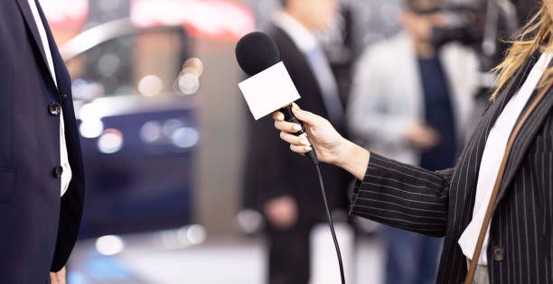 TV reporter holding microphone making press interview with unrecognizable person stock photo