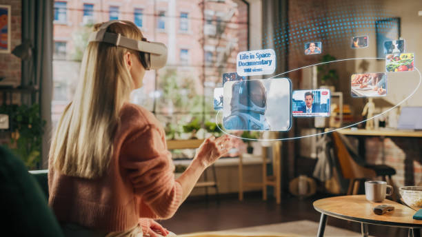 istock Woman Sitting in Loft Living Room at Home, Using Virtual Reality Headset with Controllers to Check Social Media Streaming App, Browsing Social Network Feed, Liking Posts, Watching Videos 1479355014
