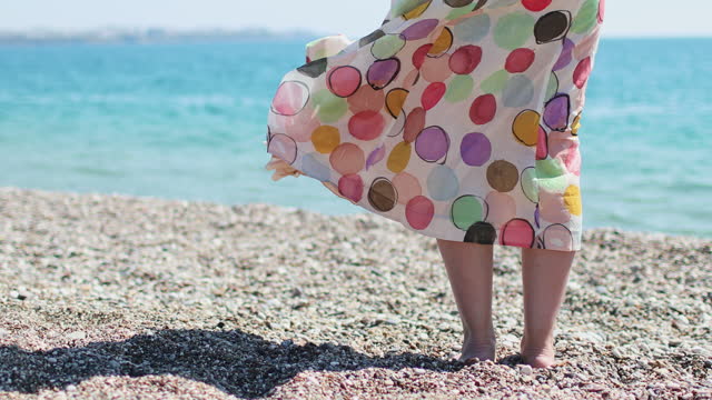 Woman's legs in skirt standing and looking at the sea