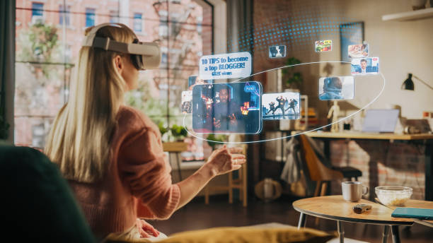 istock Woman Sitting in Loft Living Room at Home, Using Virtual Reality Headset with Controllers to Check Social Media Streaming App, Browsing Social Network Feed, Liking Posts, Watching Videos 1479355113