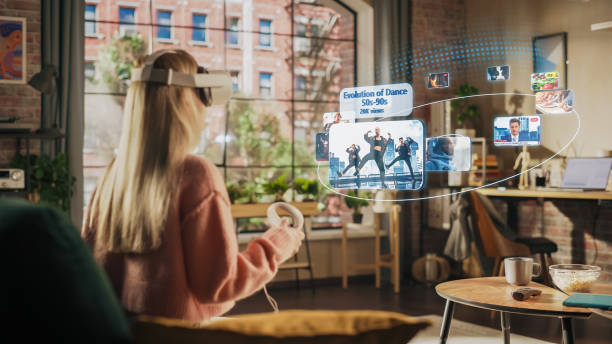 istock Woman Sitting in Loft Living Room at Home, Using Virtual Reality Headset with Controllers to Check Social Media Streaming App, Browsing Social Network Feed, Liking Posts, Watching Videos 1479355220