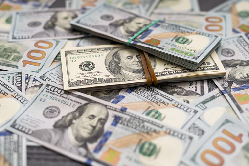 A close-up of the portrait of President George Washinton on a $1 banknote, surrounded by other US Dollar bills.