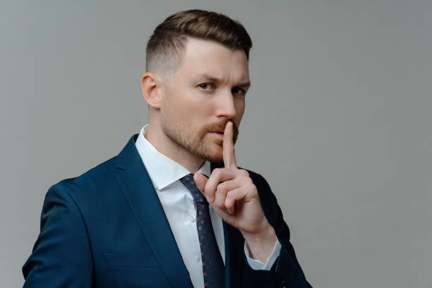 istock Serious businessman in suit showing silence sign 1479358286