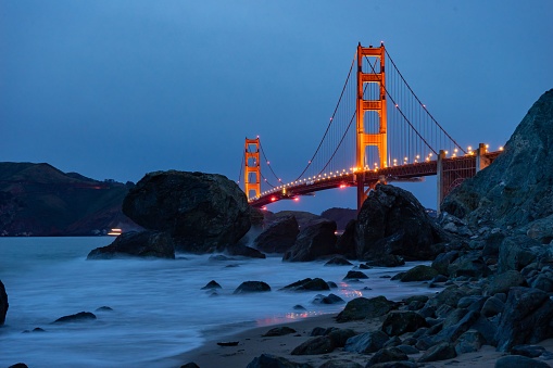 The iconic Golden Gate Bridge is seen in the foreground, illuminated with beautiful lighting
