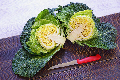 Green vegetables. Savoy cabbage head cut in half and knife on rustic table. Copy space