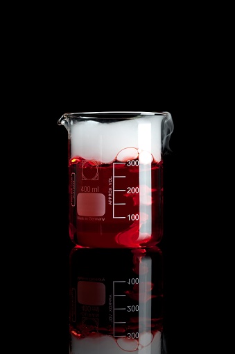 A Chemical Glasswork Beaker with Red Fluid and Smoke isolated on a Black Background
