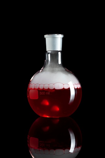 A Chemical Glasswork Flat Bottom Flask with Red Fluid and Smoke isolated Black Background