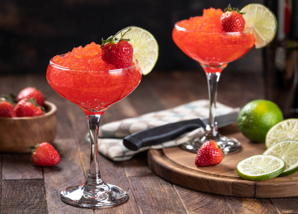 Frozen strawberry daiquiri cocktail with strawberries and lime Frozen strawberry daiquiri garnished with strawberries and lime slice on a rustic wooden background daiquiri stock pictures, royalty-free photos & images