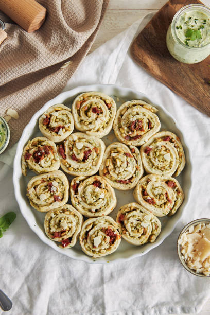 istock Vertical shot of uncookepesto pizza rolls with pine nuts and herbs butter on a white table 1479367252