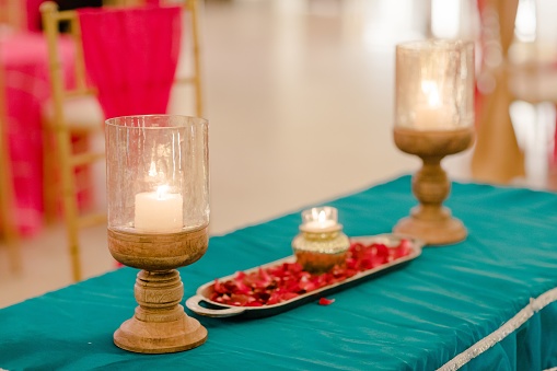 Two glass candles and vibrant flower petals on a table