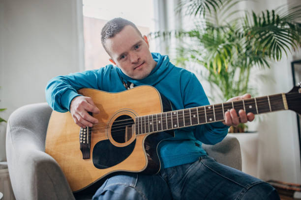 istock Down syndrome man playing a guitar in the livingroom 1479367647