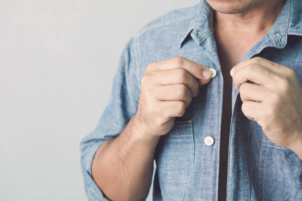 istock Man buttoning up blue jeans shirt. Studio shot on grey wall background. 1479368290