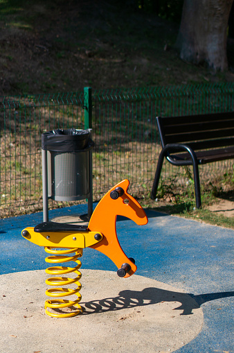 A vertical shot of orange horse-shaped swing on playground