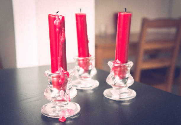 A selective focus shot of three red candles on a wooden table