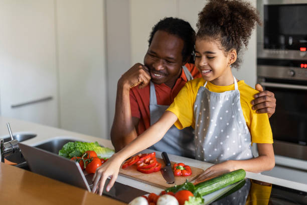 istock Black dad and his preteen daughter using laptop in kitchen while cooking 1479369559