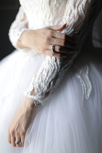 A vertical close-up of a young bride wearing her long sleeved wedding gown