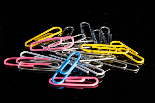 A closeup shot of a pile of colorful paper clips isolated on dark background