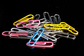 Closeup shot of a pile of colorful paper clips isolated on dark background