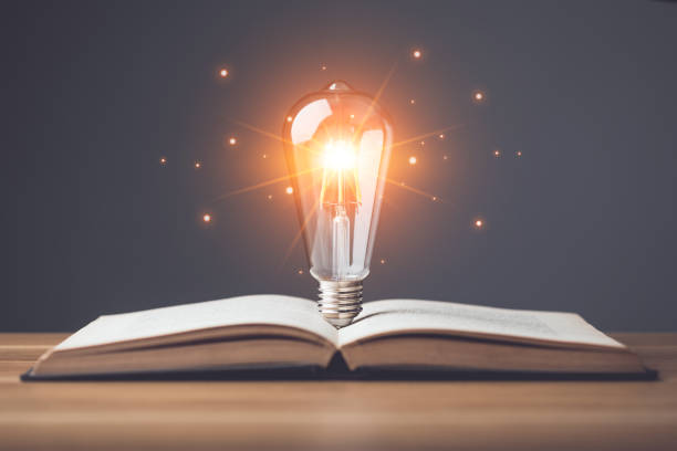 istock New inspiration for knowledge idea. Clear vintage light bulb with light effect on old book and put on wooden desk with gray space wall background. Idea of learning, Education concept. Studio shot. 1479371713