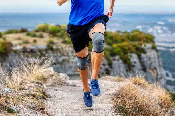 脚ランナー 膝パッドの男性が山道を走り、怪我をした後の保護膝袖を安定させる - 膝あて ストックフォトと画像