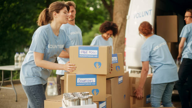 istock Happy Group of Volunteers Working on Delivering Humanitarian Aid and Donations, Loading Boxes into a Van. Charity Workers Help Members of Community. Free Meals to Unemployed, Refugees and Immigrants. 1479372392