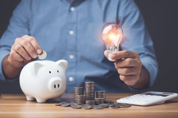 istock Financial calculate and planning, Clever yearly plan for money saving, Man holding light bulb with piggy bank, coin pile and 2023 desk calendar on the table. Studio shot on dark background 1479372403