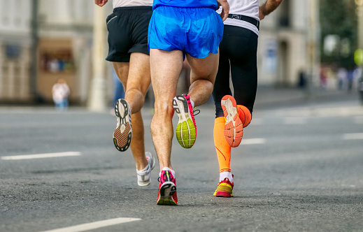 back legs three runners runing marathon, male athletes jogging city race, soles running shoes