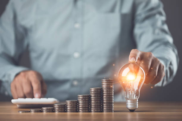 Business, Financial and money planning idea, Clever thinking about money saving for future, Man calculating number of money, increasing coin stacked and holding light bulb on the table. Studio shot. idea de planificación de negocios, finanzas y dinero, pensamiento inteligente sobre el ahorro de dinero para el futuro, hombre calculando el número de dinero, aumentando la moneda apilada y sosteniendo la bombilla sobre la mesa. foto de estudio.