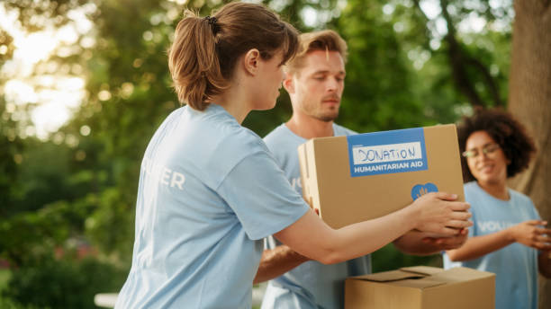 istock Positive Group of Volunteers Preparing Humanitarian Aid and Donations, Loading Boxes in a Cargo Van. Charity Workers Help Members of the Community. Free Meals to Unemployed, Refugees and Immigrants. 1479375171
